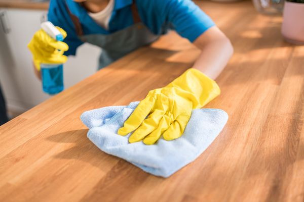 Professional cleaner wiping a kitchen counter with a microfiber cloth