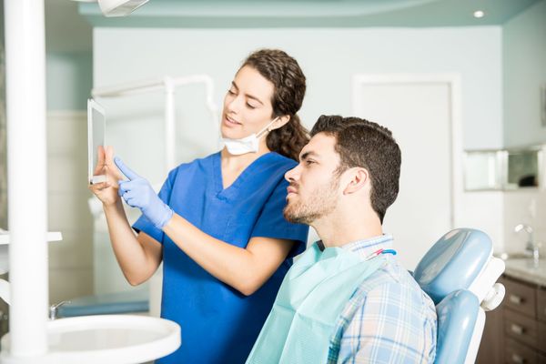 Dentist showing a patient information on a tablet in a modern clinic