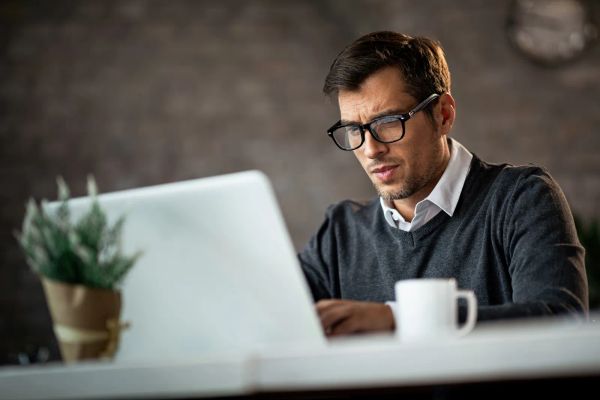 Business owner typing an email on a laptop at work