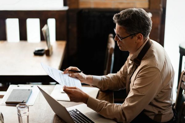 Small business owner reviewing paperwork and policies at a table in his shop