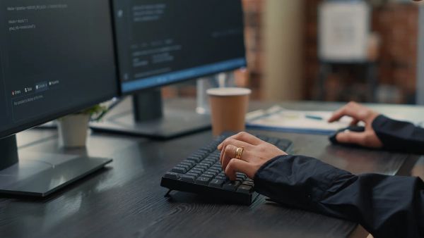 Web developer typing schema markup code on a keyboard with code on screen