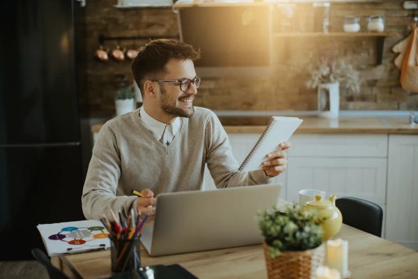 Business owner reviewing name ideas in a notebook at a laptop