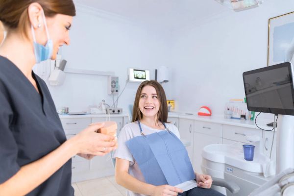 Dentist showing a teeth model to a smiling patient