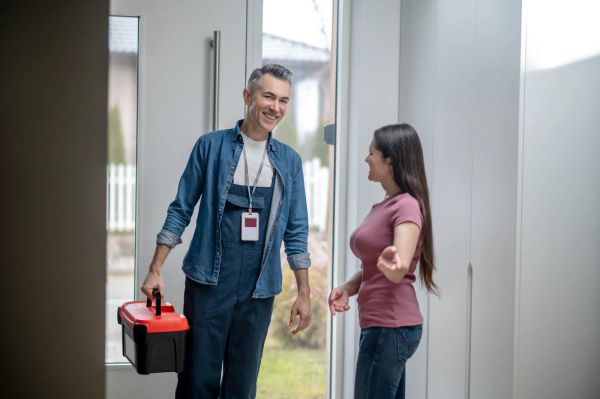 Homeowner welcoming a tradesman with his tools into her house