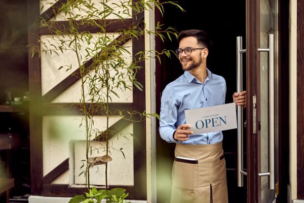 Cafe owner hanging an open sign on the front door