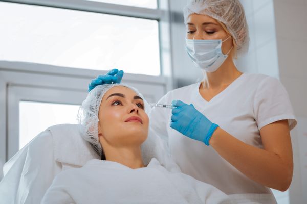 Professional aesthetic injector performing a treatment on a calm client at a modern med spa