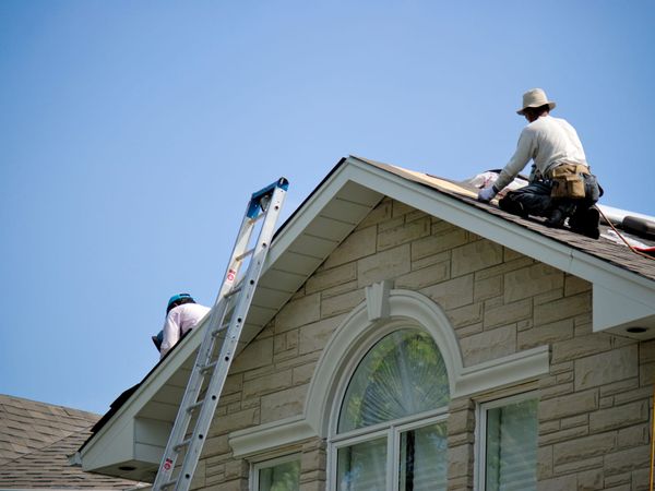 Professional roofing crew installing a new roof on a residential home under a blue sky