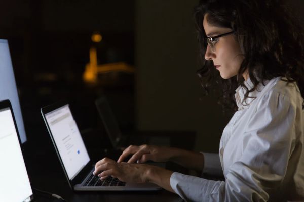 Businesswoman using a laptop in a dark office at night