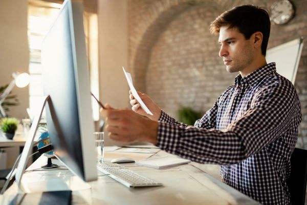 Entrepreneur comparing options across business reports at a desk