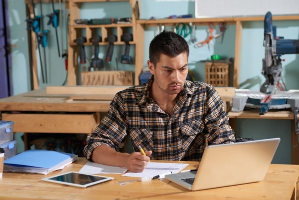 Small business owner planning his website budget on a laptop in his workshop