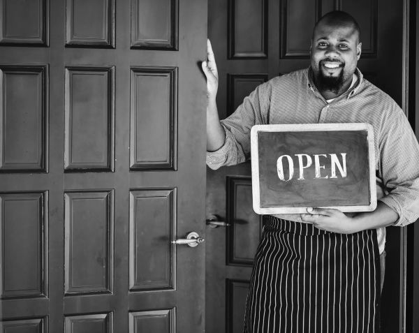Cheerful local business owner holding an open sign at her storefront